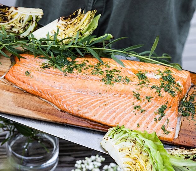 Grilled salmon on a plank with herb oil, potatoes and grilled cabbage