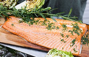 Grilled salmon on a plank with herb oil, potatoes and grilled cabbage